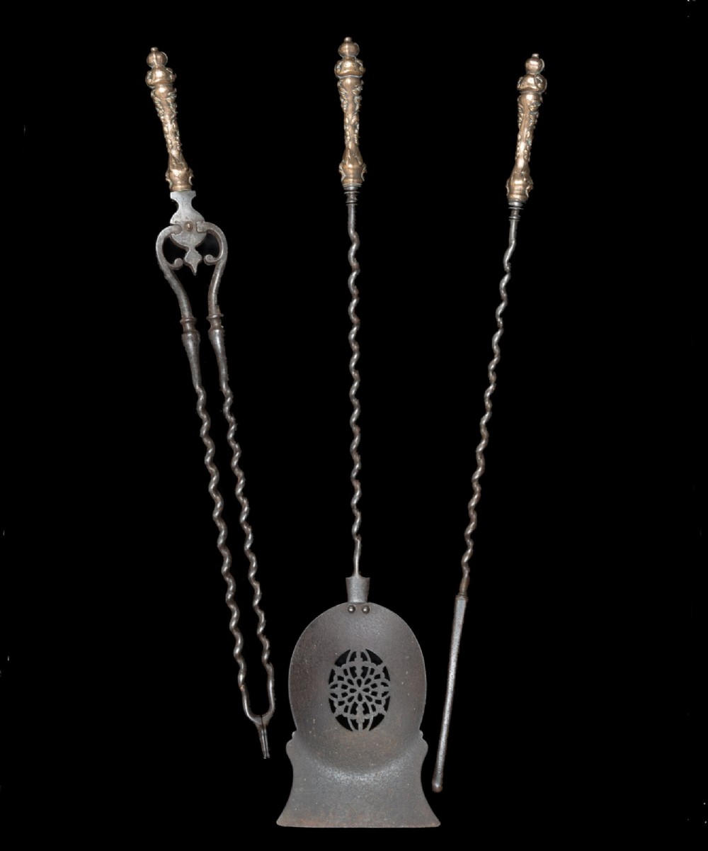 A three-piece set of nineteenth-century fire irons featuring ornate cast brass handles, spiral-twisted steel shafts, and a pierced pan shovel.