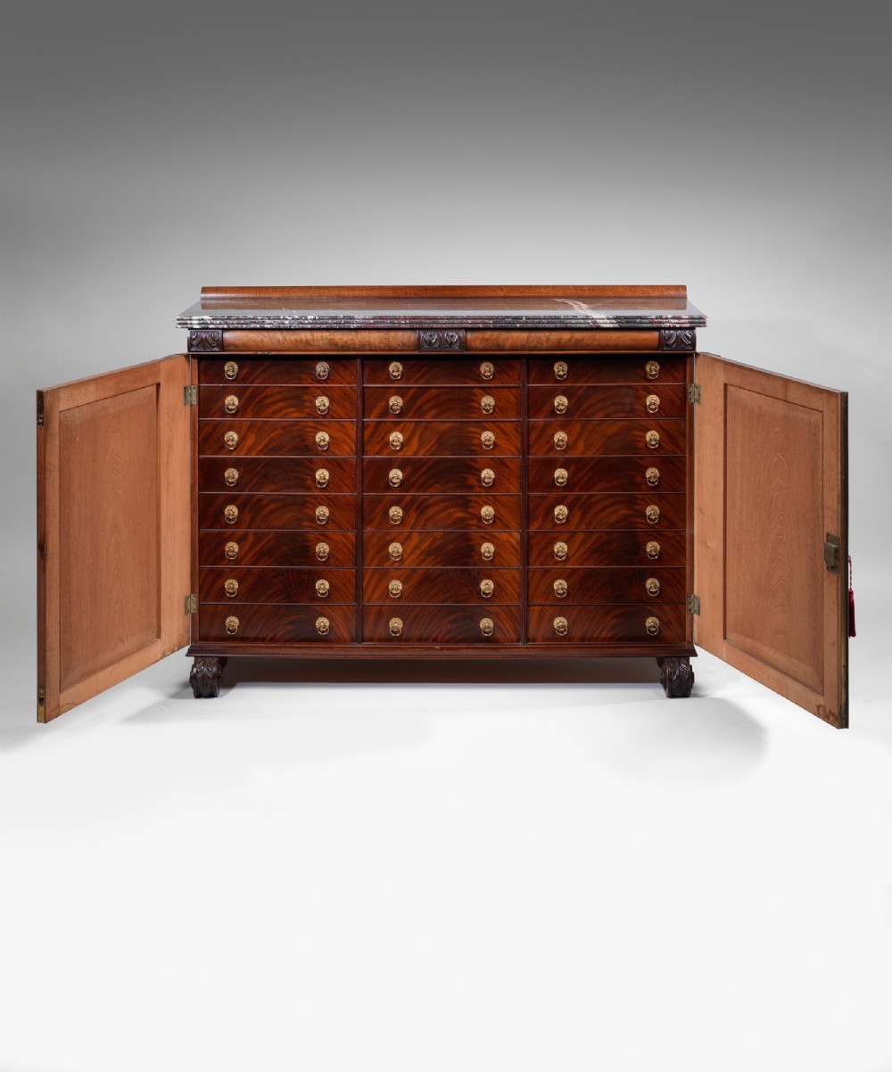 A Regency flame mahogany cabinet featuring a grey veined marble top, double panelled doors, and carved acanthus leaf pilasters. View II