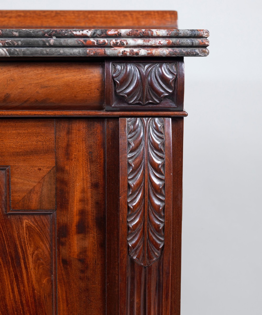 A Regency flame mahogany cabinet featuring a grey veined marble top, double panelled doors, and carved acanthus leaf pilasters. View III