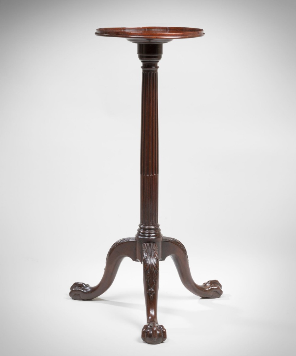 A tall Georgian mahogany torchere featuring a molded dish top, fluted central column, and carved tripod cabriole legs terminating in claw and ball feet.