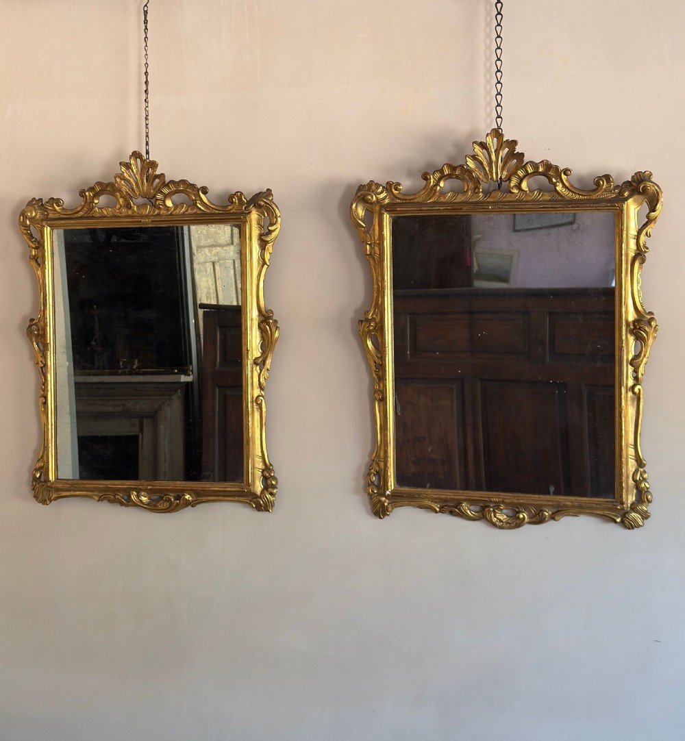 A symmetrical pair of rectangular wall mirrors framed in carved gold giltwood with acanthus leaf cresting and rococo scroll details. View II