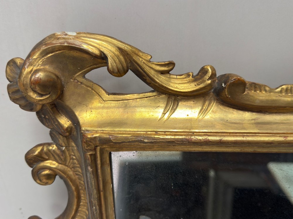 A symmetrical pair of rectangular wall mirrors framed in carved gold giltwood with acanthus leaf cresting and rococo scroll details. View VI
