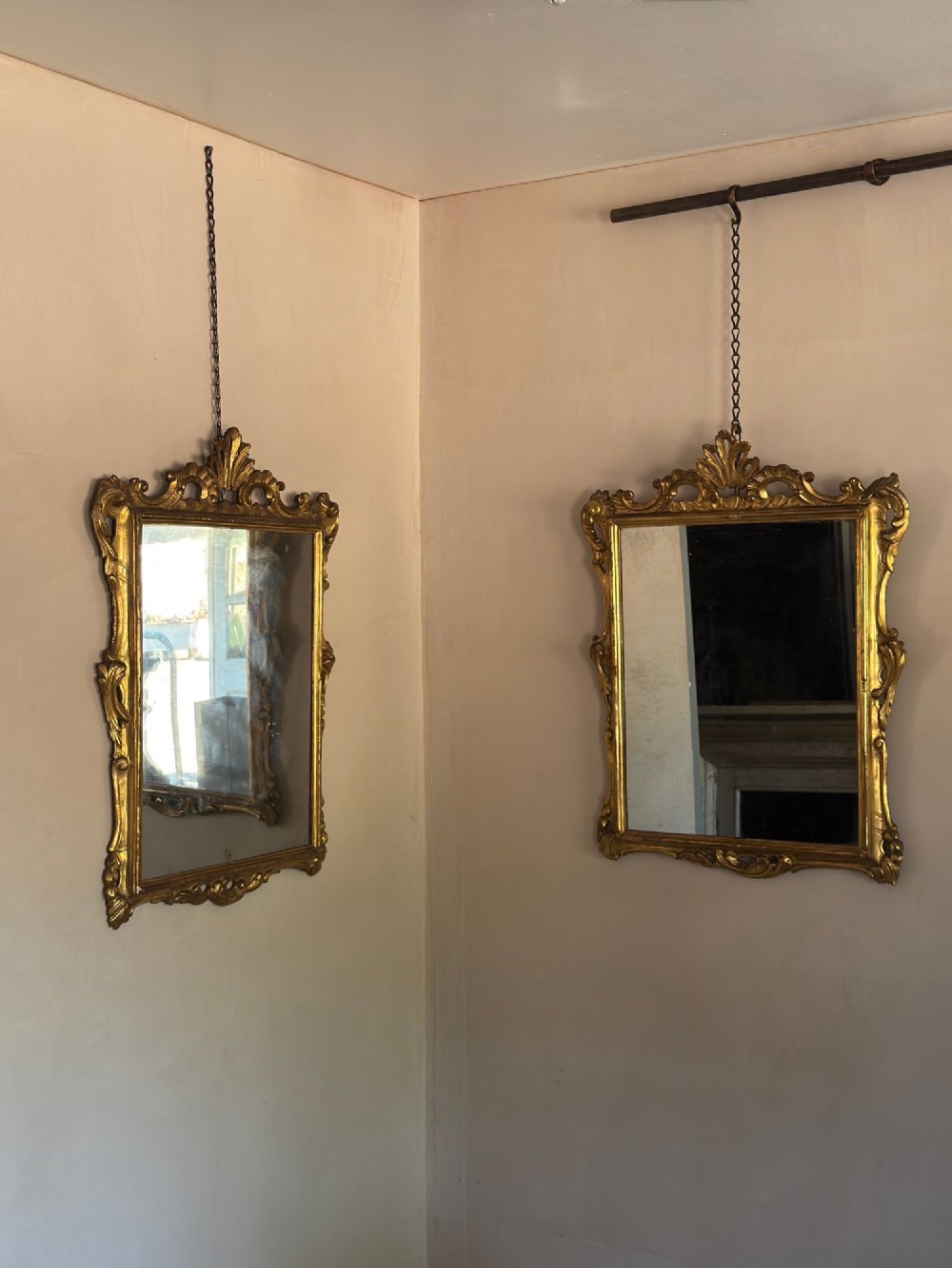 A symmetrical pair of rectangular wall mirrors framed in carved gold giltwood with acanthus leaf cresting and rococo scroll details. View VII