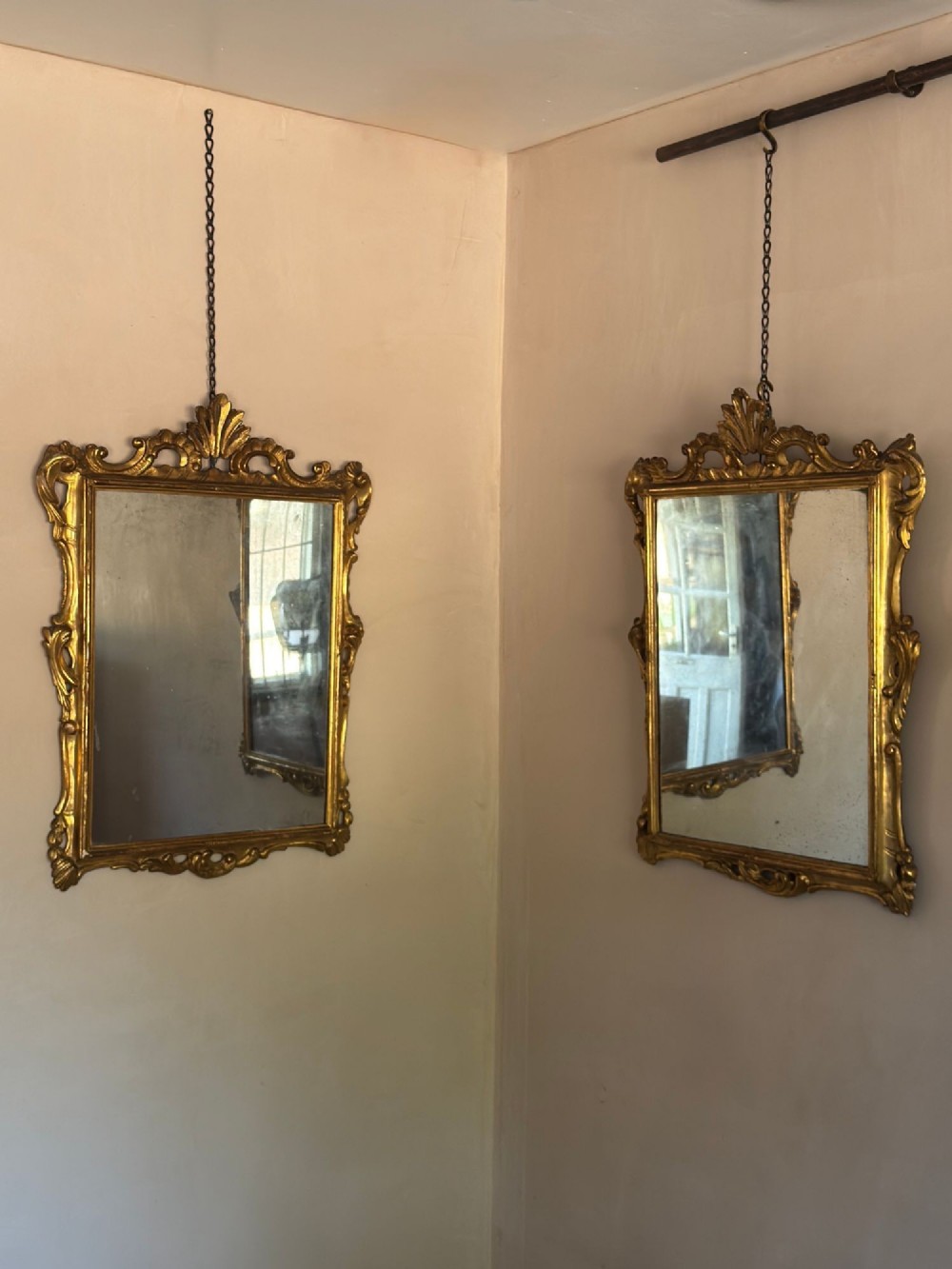 A symmetrical pair of rectangular wall mirrors framed in carved gold giltwood with acanthus leaf cresting and rococo scroll details. View VIII