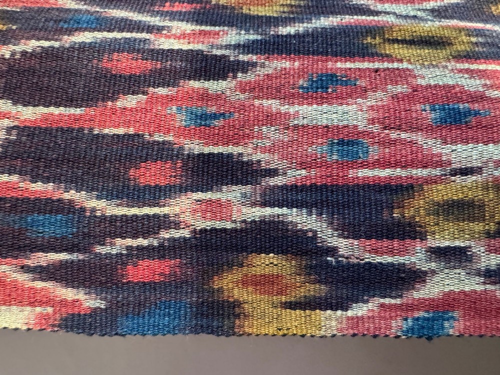 A vertical handwoven Sumba ikat hinggi textile featuring diamond lattice patterns in terracotta red, dark indigo, and yellow with zoomorphic border bands and lower fringe. View VIII