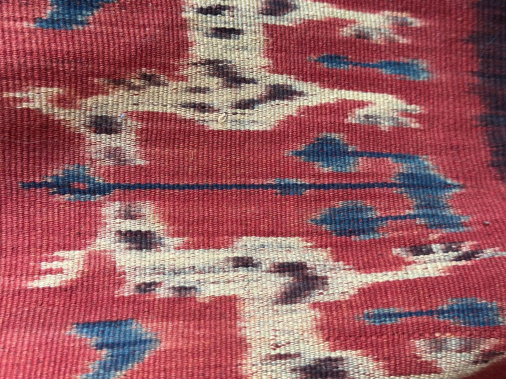 A vertical handwoven Sumba ikat hinggi textile featuring diamond lattice patterns in terracotta red, dark indigo, and yellow with zoomorphic border bands and lower fringe. View IX