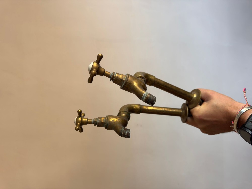 A pair of reclaimed antique brass bib taps with crosshead handles mounted on extended brass standpipes. View II