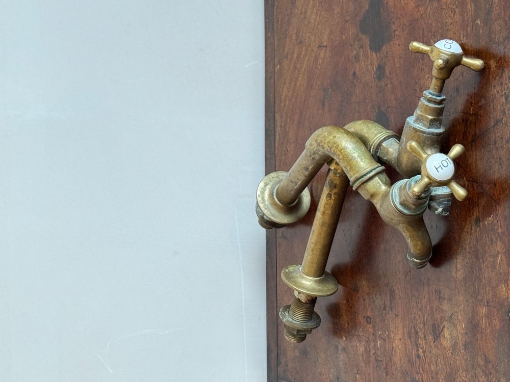 A pair of reclaimed antique brass bib taps with crosshead handles mounted on extended brass standpipes. View III