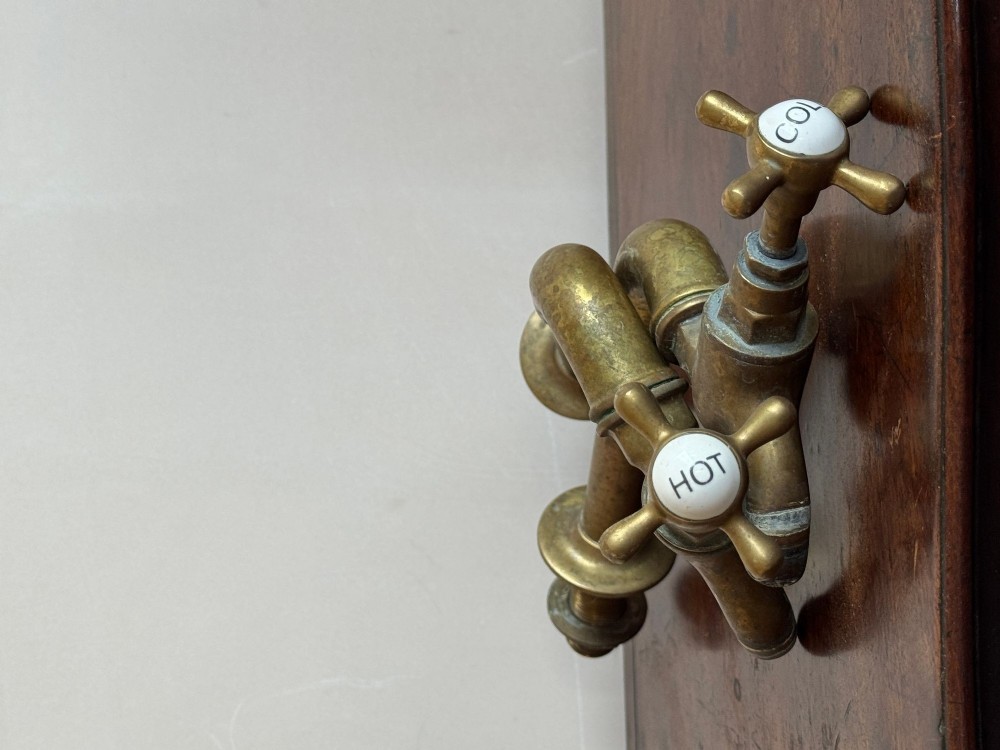 A pair of reclaimed antique brass bib taps with crosshead handles mounted on extended brass standpipes. View IV