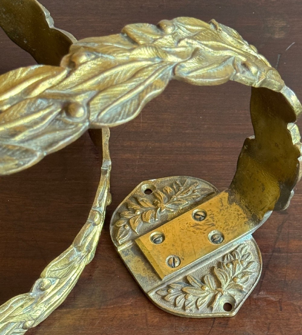 A pair of 19th-century gilt brass curtain tie-backs featuring cast foliage motifs and round mounting plates. View II