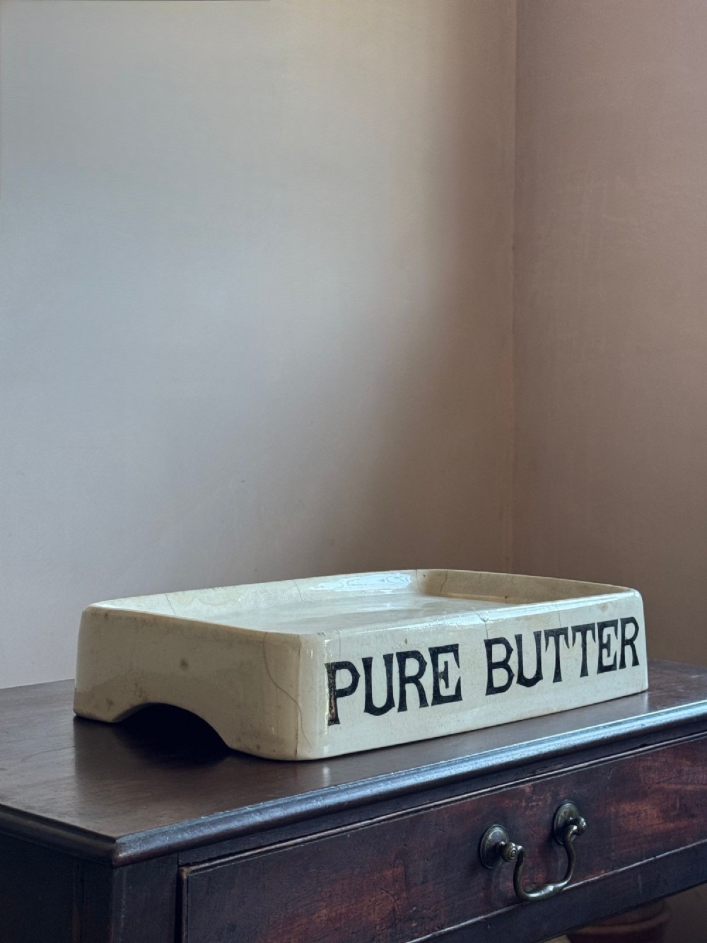 A rectangular cream ceramic grocers slab with black transfer-printed typography reading PURE BUTTER on the front edge.