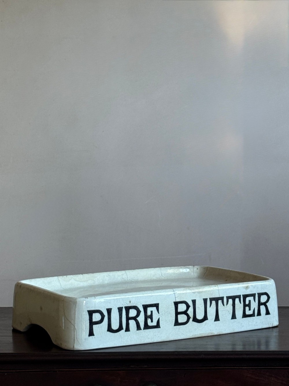 A rectangular cream ceramic grocers slab with black transfer-printed typography reading PURE BUTTER on the front edge. View II