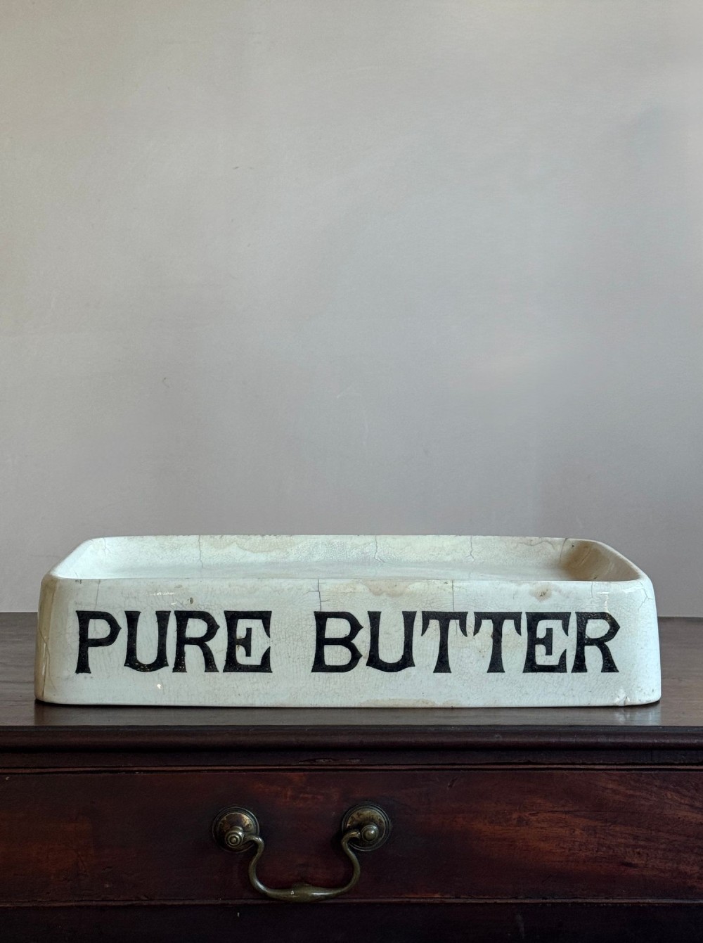 A rectangular cream ceramic grocers slab with black transfer-printed typography reading PURE BUTTER on the front edge. View III