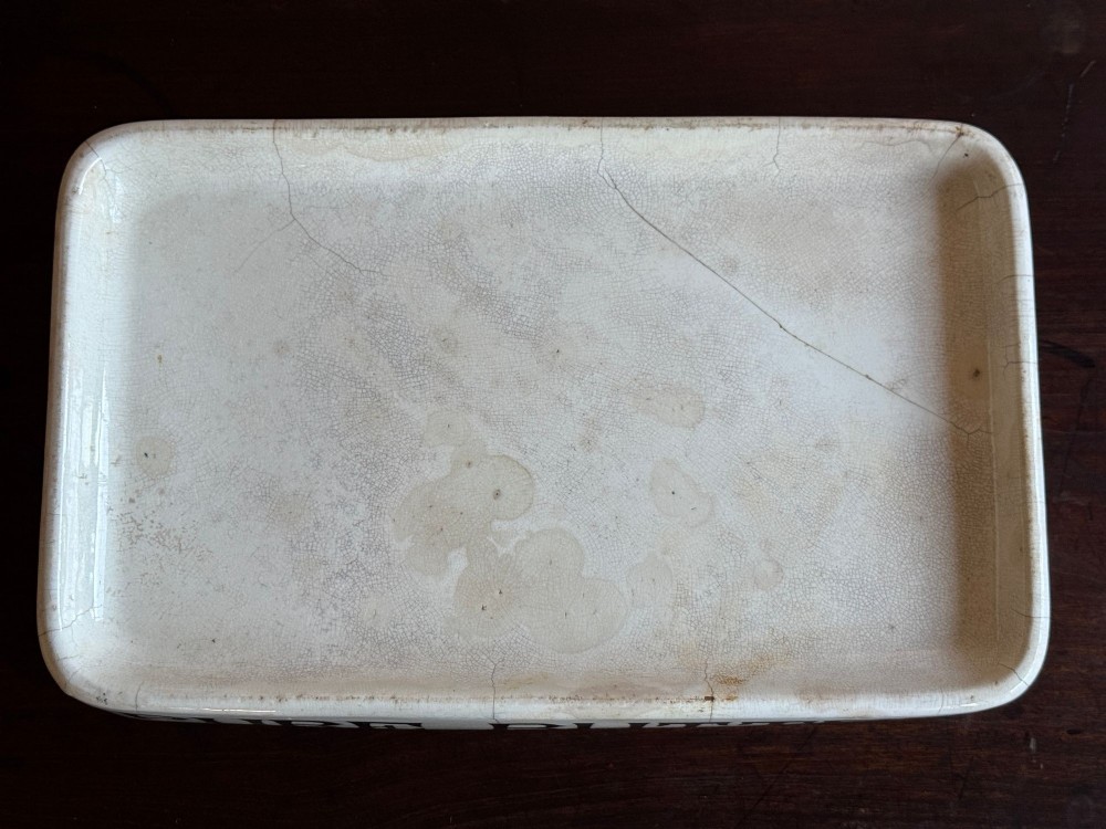 A rectangular cream ceramic grocers slab with black transfer-printed typography reading PURE BUTTER on the front edge. View V
