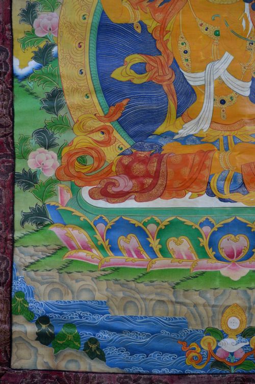 A Tibetan Thangka scroll depicting the seated deity Manjushri holding a raised sword and lotus stem, framed with a patterned silk border. View IV