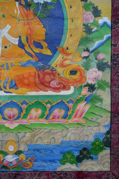 A Tibetan Thangka scroll depicting the seated deity Manjushri holding a raised sword and lotus stem, framed with a patterned silk border. View V