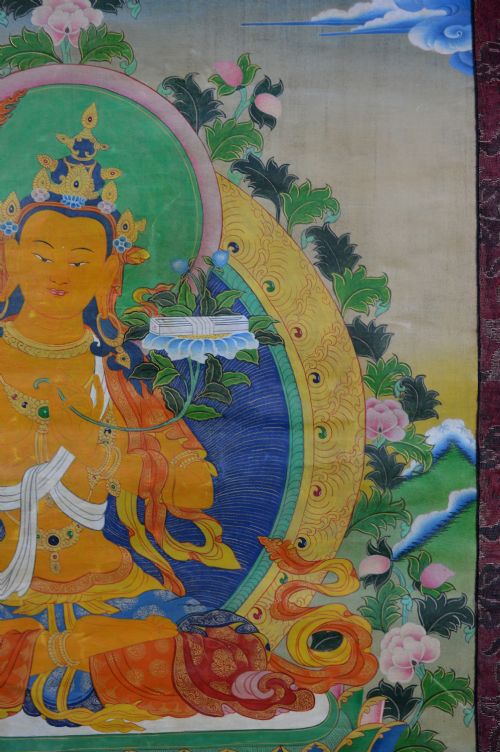 A Tibetan Thangka scroll depicting the seated deity Manjushri holding a raised sword and lotus stem, framed with a patterned silk border. View VII