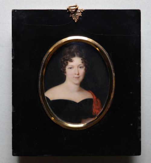 fig 1. An oval portrait miniature painting depicting a woman with dark curly hair in a black off-the-shoulder dress, set in a beaded gilt brass bezel within a black frame.