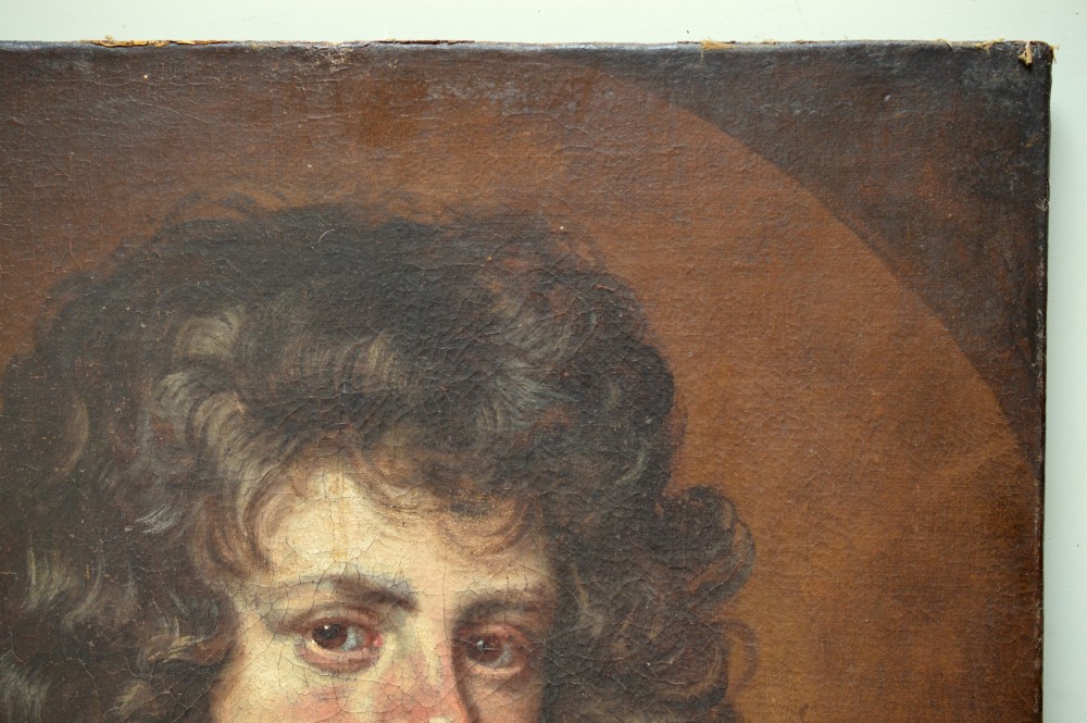 An antique oil portrait painting depicting a young gentleman with dark voluminous curls, wearing a white lace cravat and red mantle within a feigned oval frame. View VII
