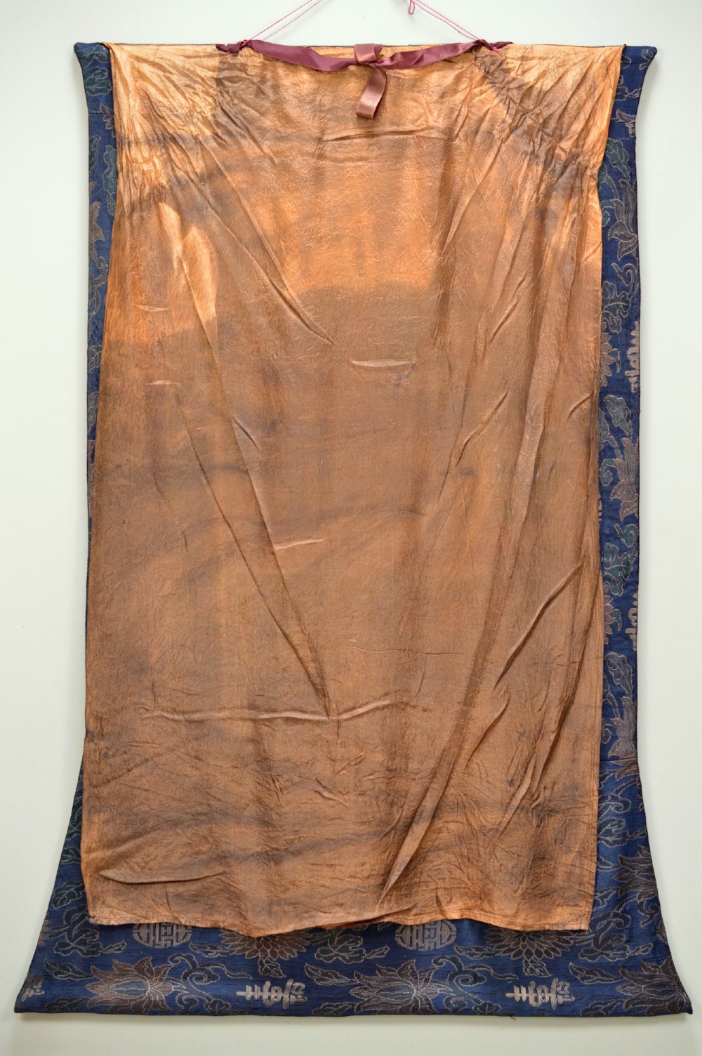 A Tibetan Thangka scroll depicting the seated deity Manjushri holding a raised sword and lotus stem, framed with a patterned silk border. View IX