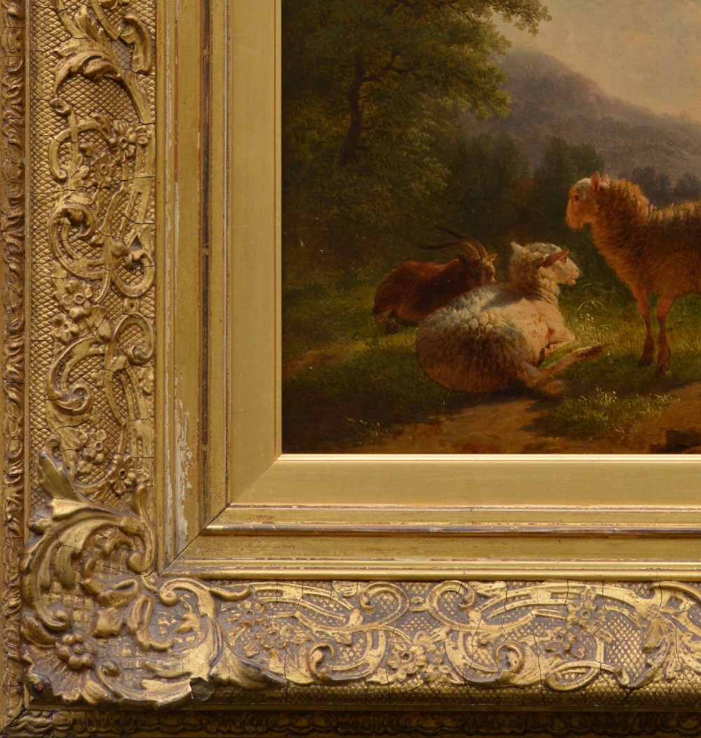 An antique oil painting depicting sheep and a goat in a green pastoral landscape surrounded by an ornate gold giltwood frame. View II