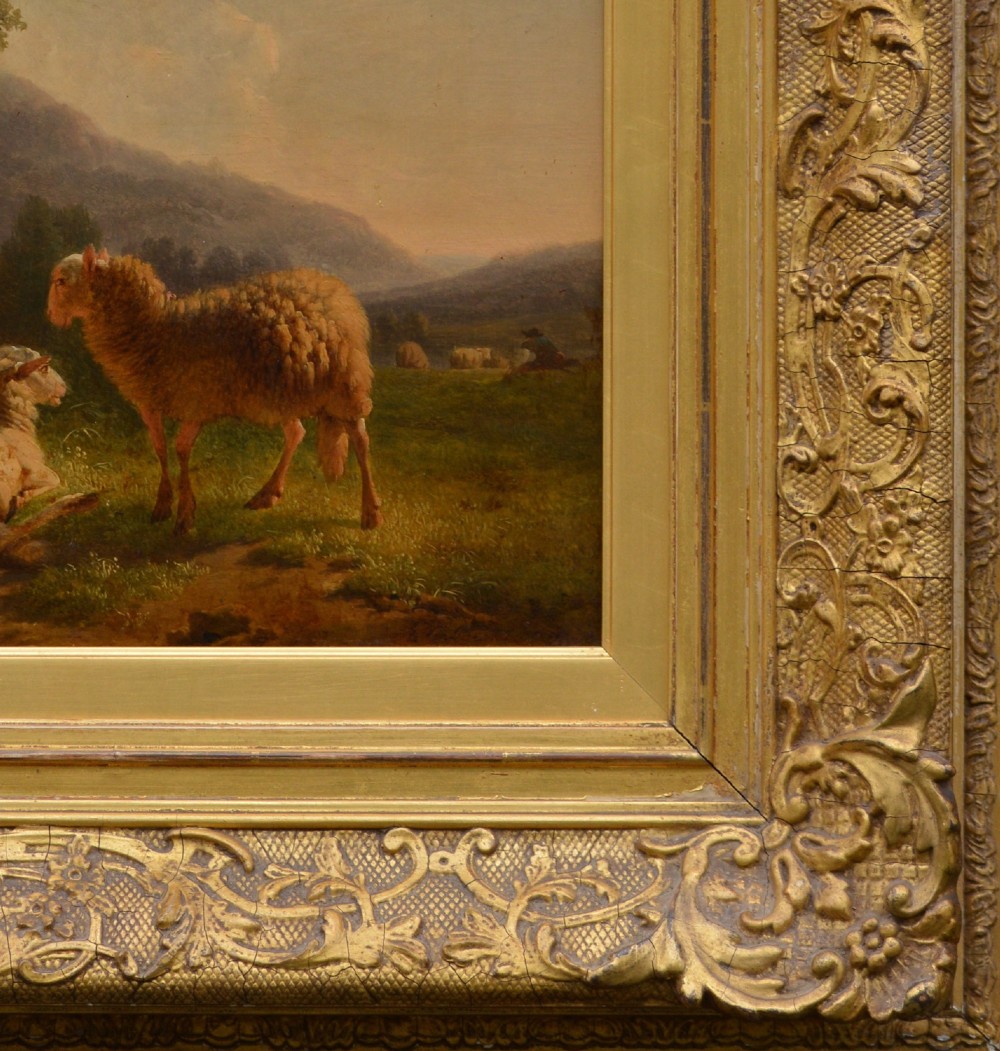 An antique oil painting depicting sheep and a goat in a green pastoral landscape surrounded by an ornate gold giltwood frame. View III