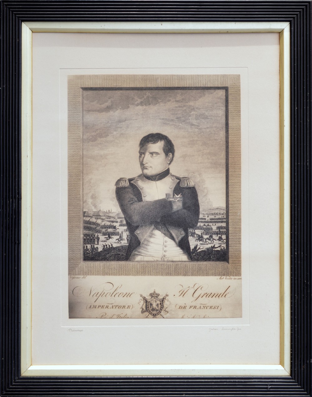 A framed monochrome portrait print depicting Napoleon Bonaparte in military dress with crossed arms, housed within a cream mount and a dark ebonised reeded frame.