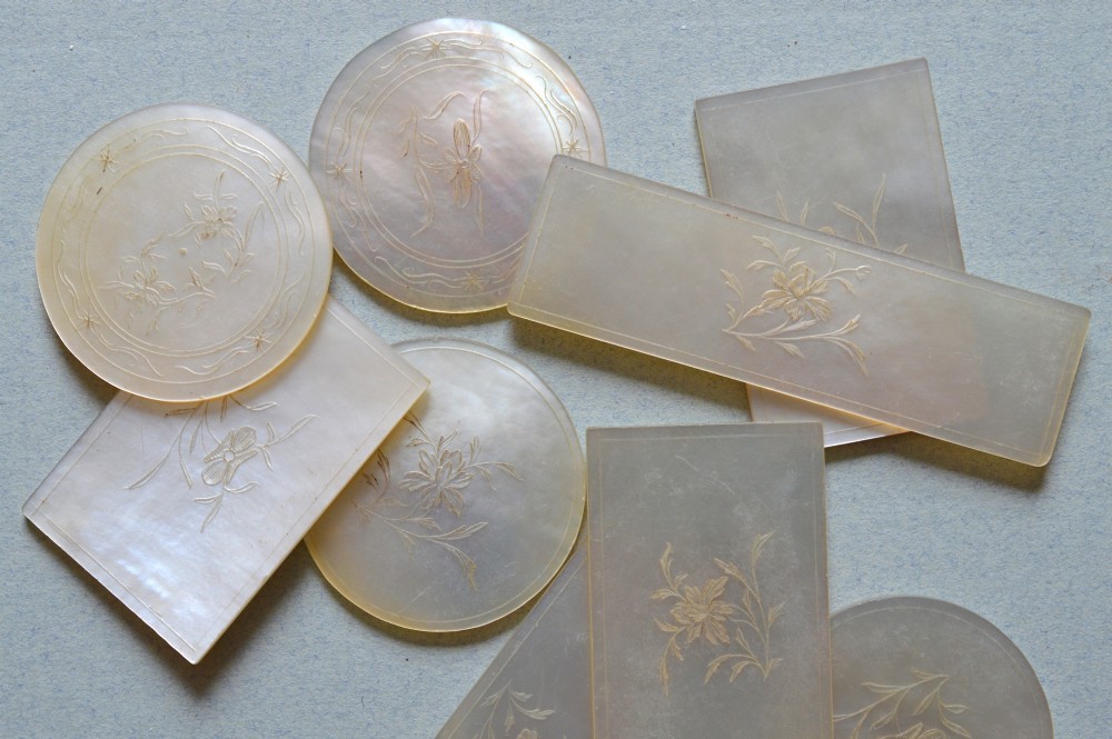 A collection of 126 engraved Chinese mother of pearl gaming counters in round and rectangular shapes arranged inside a fitted wooden tray. View II