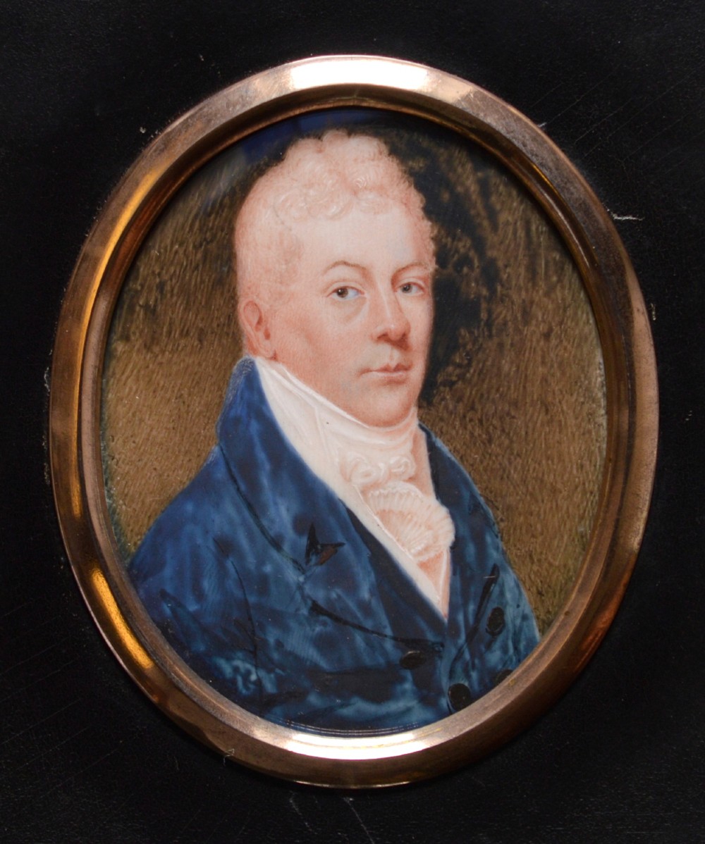 An oval late 18th-century watercolour portrait miniature depicting a gentleman wearing a blue coat and white cravat inside a metal bezel.