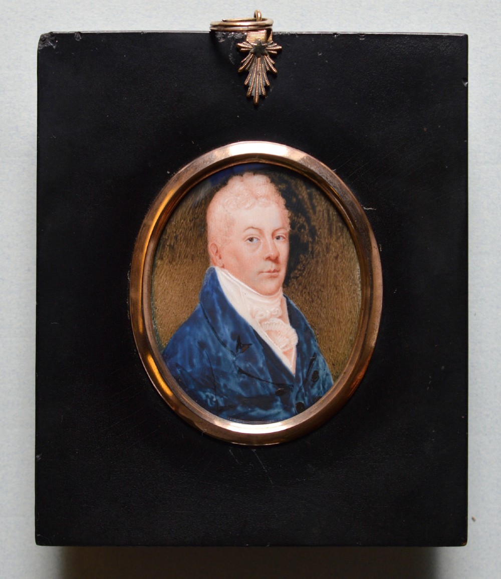 An oval late 18th-century watercolour portrait miniature depicting a gentleman wearing a blue coat and white cravat inside a metal bezel. View II