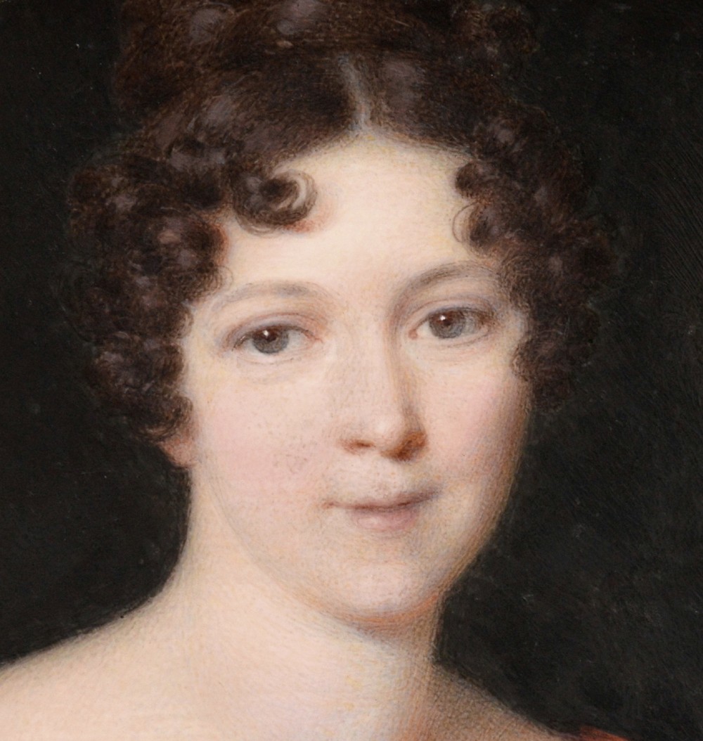An oval portrait miniature painting depicting a woman with dark curly hair in a black off-the-shoulder dress, set in a beaded gilt brass bezel within a black frame. View IV
