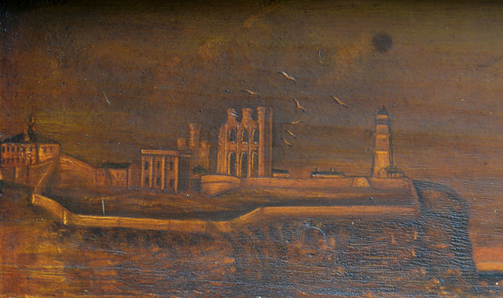 A 19th-century framed wooden folk art diorama featuring a relief-carved half hull coble boat set against a painted view of Tynemouth Castle and Priory. View XIII