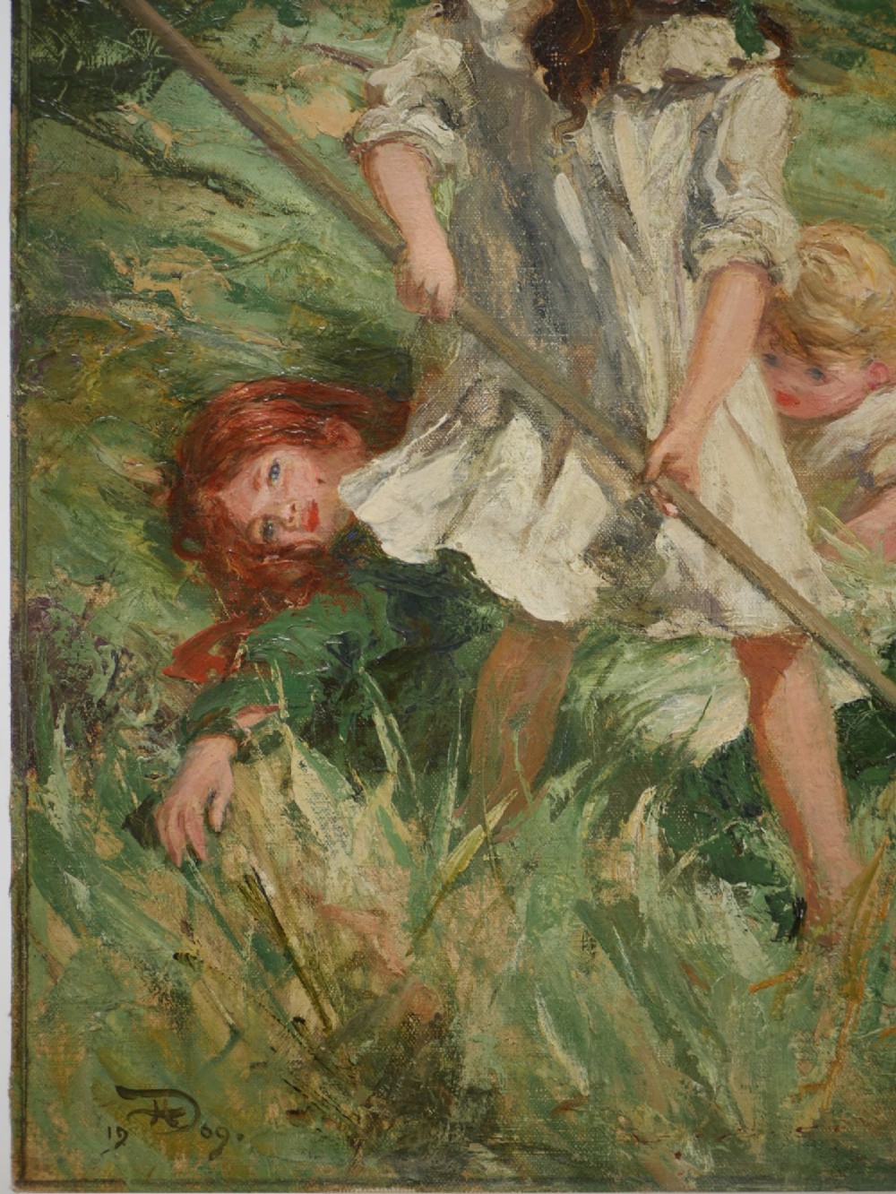 An Edwardian oil painting on board depicting three children in a green field, presented inside a moulded gold gilt frame. View III