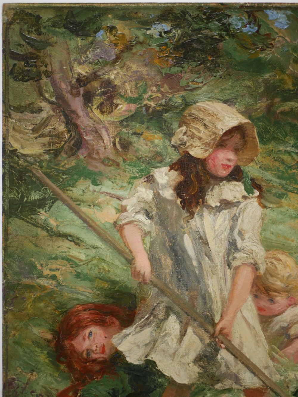 An Edwardian oil painting on board depicting three children in a green field, presented inside a moulded gold gilt frame. View IV