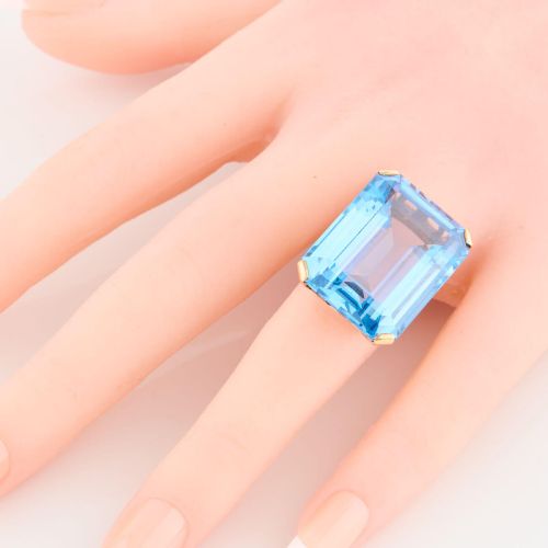 fig 1. A 9ct gold vintage dress ring featuring a large emerald-cut light blue paste stone held in a raised basket setting.