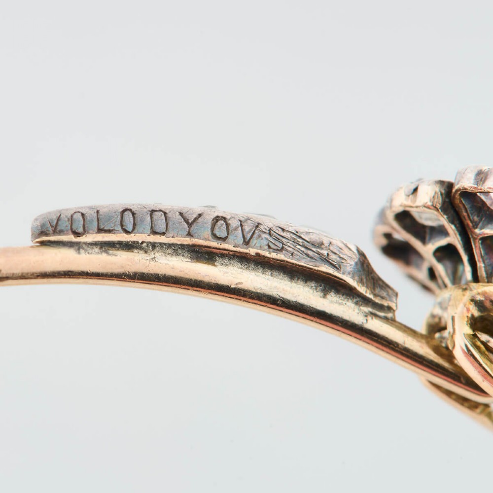 A hinged gold bangle featuring a central diamond-set floral cluster motif flanked by diamond-set shoulders. View VI