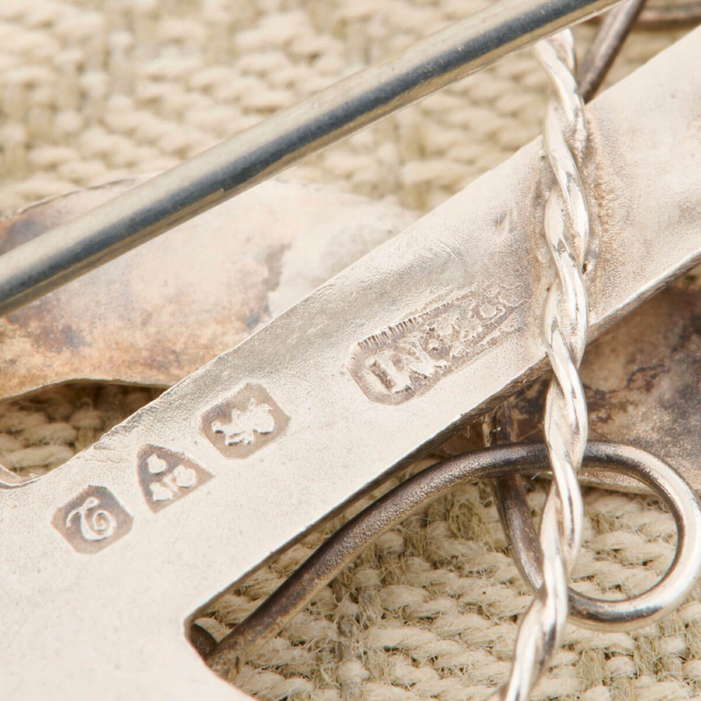 An antique silver anchor brooch featuring coiled rope wirework, two rose gold flowers, and a blank central rose gold scroll banner. View VI