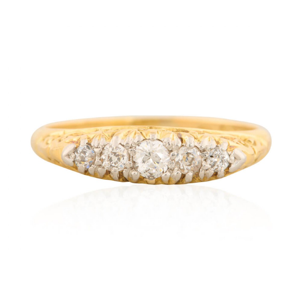 An antique 18ct yellow gold ring featuring five graduated round cut diamonds set in a carved gold gallery.