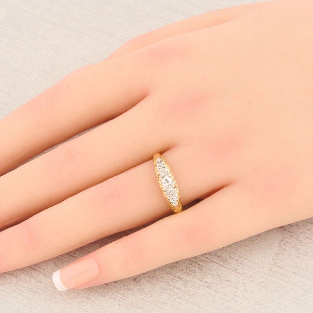 An antique 18ct yellow gold ring featuring five graduated round cut diamonds set in a carved gold gallery. View II