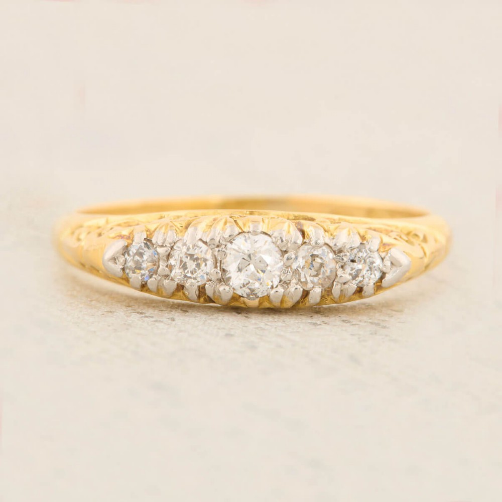 An antique 18ct yellow gold ring featuring five graduated round cut diamonds set in a carved gold gallery. View III