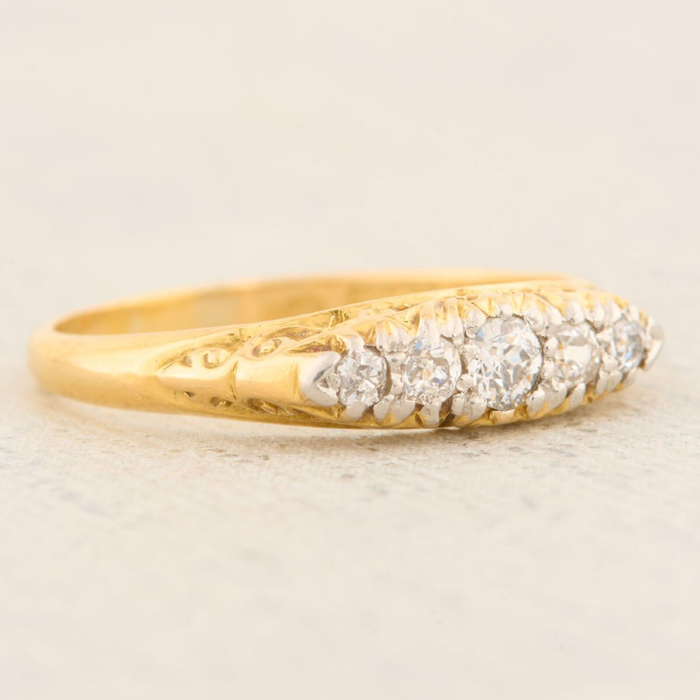 An antique 18ct yellow gold ring featuring five graduated round cut diamonds set in a carved gold gallery. View IV
