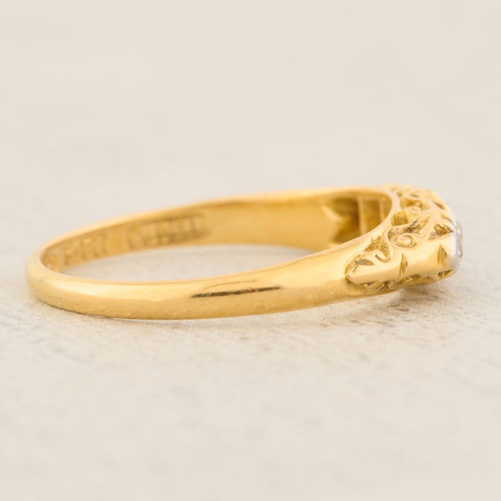 An antique 18ct yellow gold ring featuring five graduated round cut diamonds set in a carved gold gallery. View V
