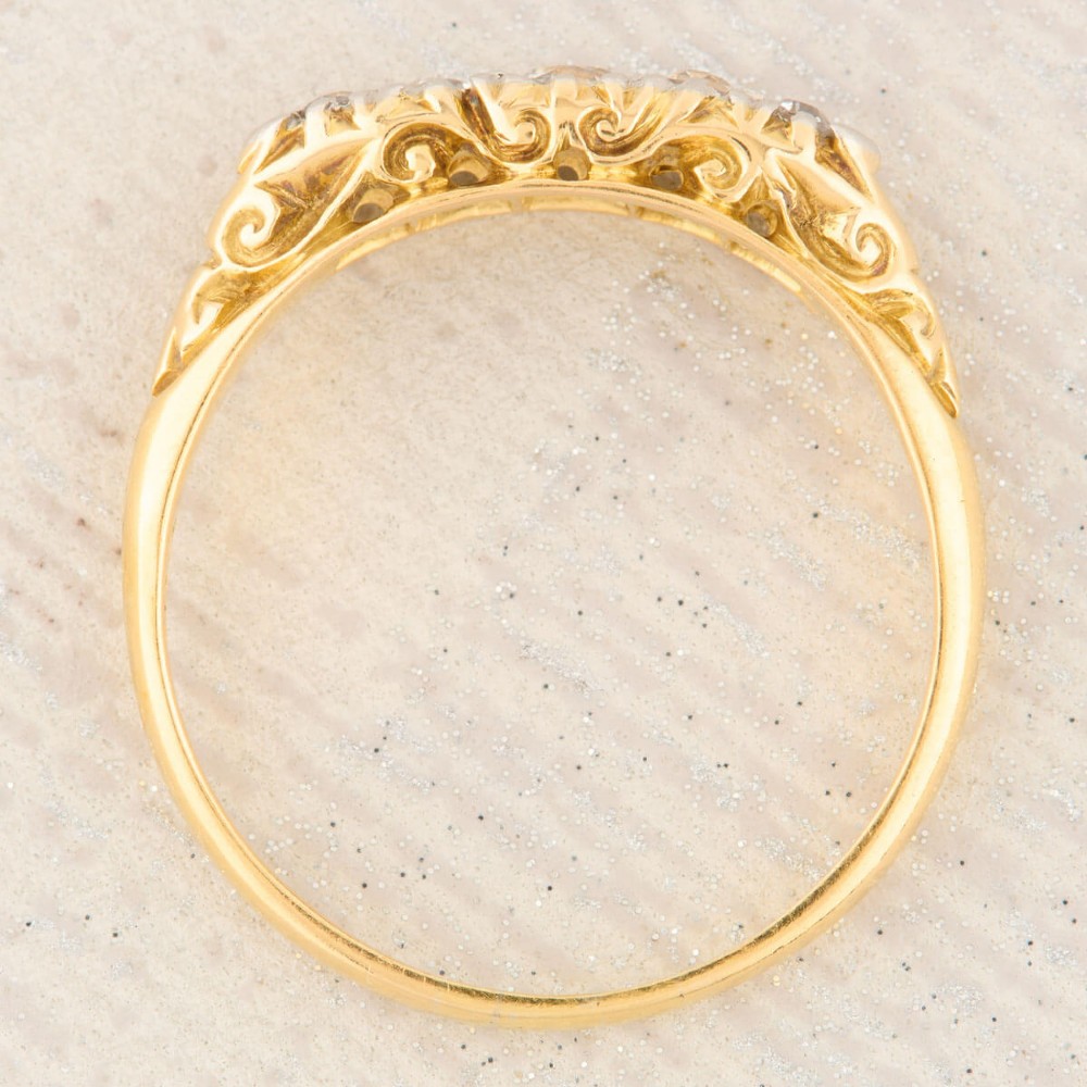 An antique 18ct yellow gold ring featuring five graduated round cut diamonds set in a carved gold gallery. View VII