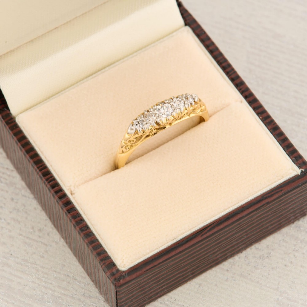 An antique 18ct yellow gold ring featuring five graduated round cut diamonds set in a carved gold gallery. View IX