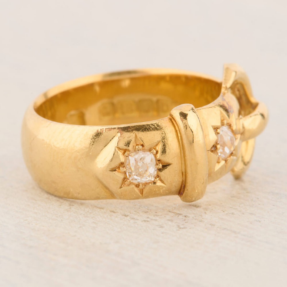 An 18ct yellow gold band shaped as a belt buckle with two star-set diamond accents. View IV