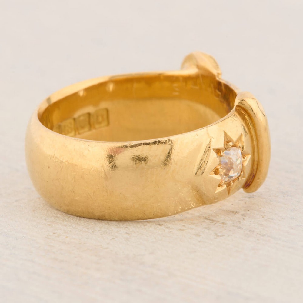 An 18ct yellow gold band shaped as a belt buckle with two star-set diamond accents. View V