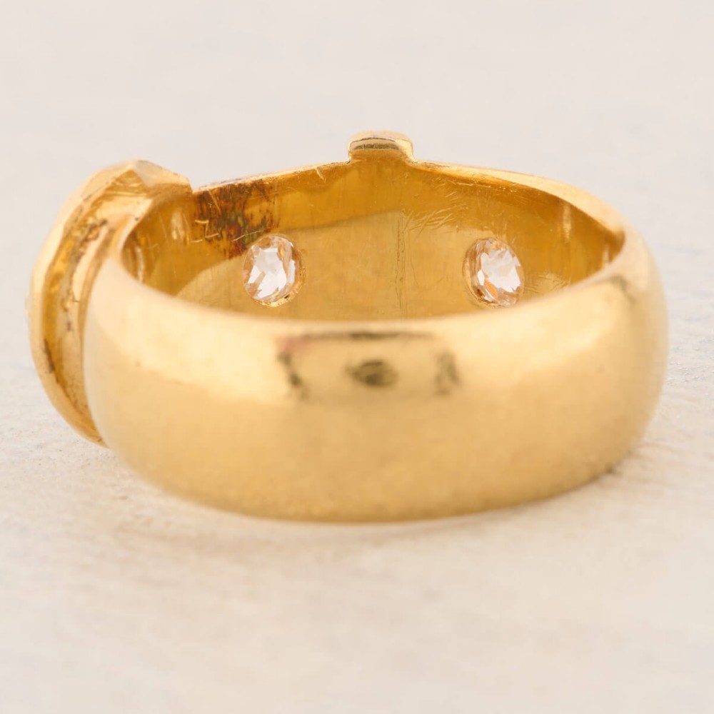 An 18ct yellow gold band shaped as a belt buckle with two star-set diamond accents. View VI