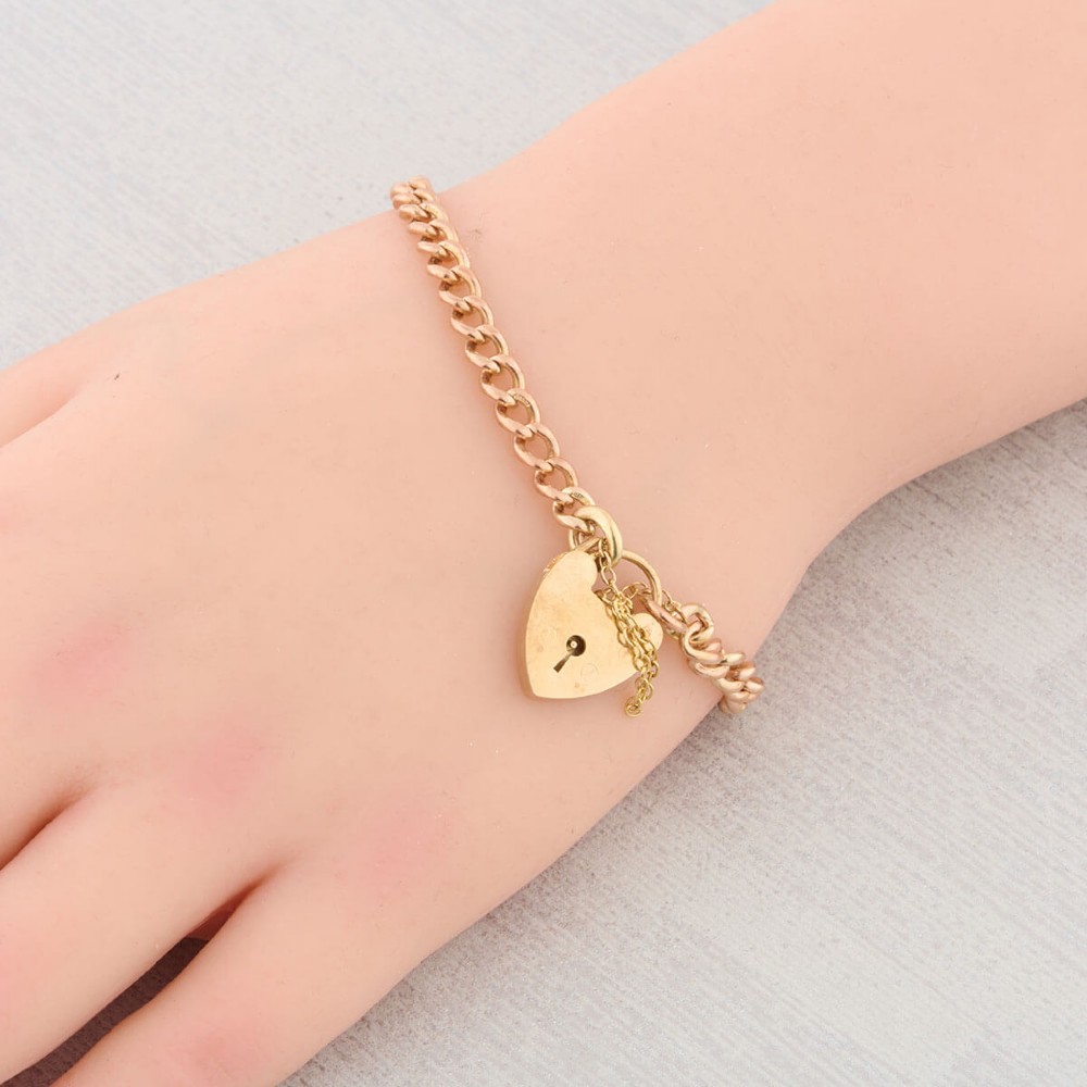 A 9ct rose gold curb chain bracelet featuring a heart-shaped padlock clasp with an attached safety chain. View II