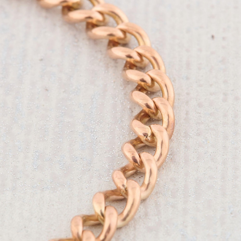 A 9ct rose gold curb chain bracelet featuring a heart-shaped padlock clasp with an attached safety chain. View VII
