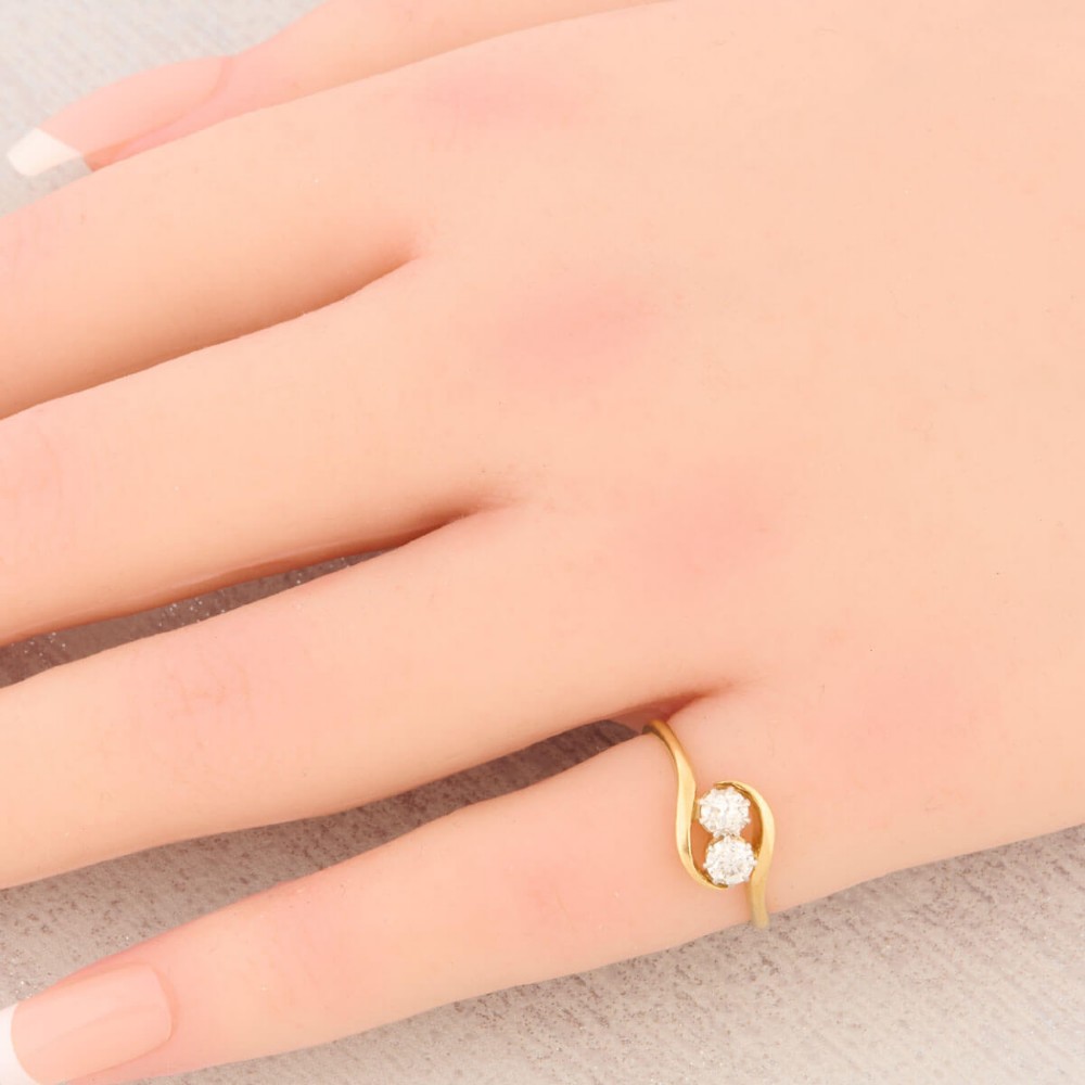 An 18ct yellow gold crossover bypass ring featuring two claw-set round brilliant diamonds. View II